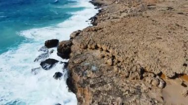 Sea washes the rocky shore, Above Aerial shot, Flying Over Coastline, Cliffside with Blue Pure Water, Ocean During Sunny weather. Bird Eye View 4K Cinematic Drone Footage. Coast From the Air, Cyprus