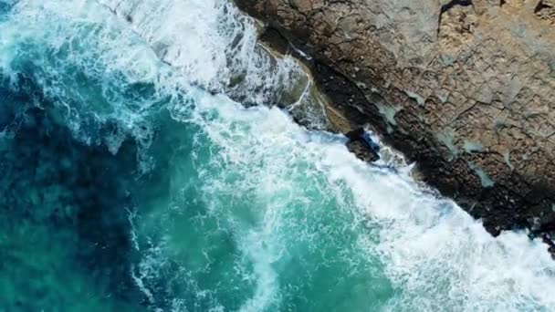 海は、空中で撮影された上方の岩だらけの海岸線を洗い、海岸線を飛び、青い純水と崖側で、海晴れた天候の間に。バード・アイ・ビュー4Kシネマティック・ドローン映像。キプロスの空から — ストック動画