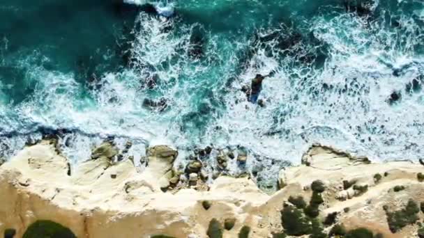 Imagens aéreas de 4k por drone de ondas azuis do oceano quebram em um penhasco alto de uma montanha rochosa. Ondas marinhas perigosas em uma praia — Vídeo de Stock