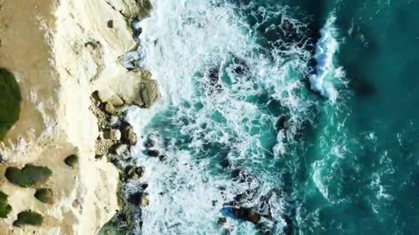 Vista aérea de imágenes de 4k por dron de olas azules del océano rompen en el alto acantilado de una montaña rocosa. Peligro olas de mar en una playa — Vídeos de Stock