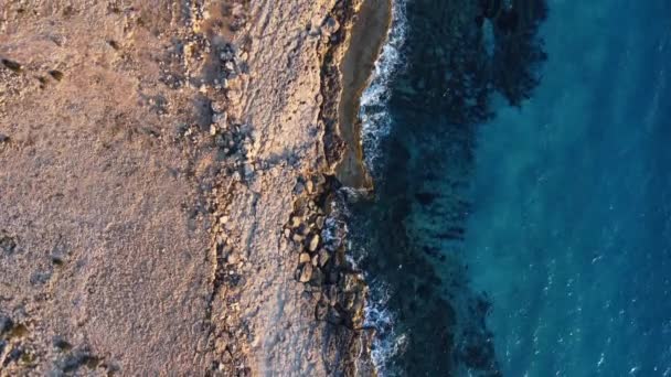 Volando sobre la costa rocosa, acantilados en el mar azul, paisaje oceánico durante la puesta del sol. Bird Eye View 4K Cinematic Drone Filmación. Costa del Mar Desde el aire, Chipre — Vídeos de Stock