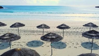 Deniz kenarında şemsiyeleri olan boş kumlu bir sahil, güneşli bir hava. Tatiller ve tatiller yazın cennet kıyısında, Aerial view, Kıbrıs