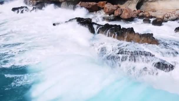 Luftbild der Wellen brechen auf Felsen in einem blauen Ozean, Meereswellen am schönen Strand Vogelperspektive der Ozeanwellen kracht gegen eine leere Steinklippe von oben, Zypern — Stockvideo