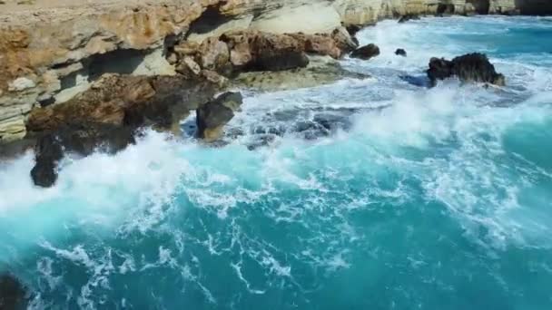 青い海の岩の上の波の空中ビュー、美しいビーチの海の波上から空の石の岩の崖に対してクラッシュ海の波の鳥の目のビュー、キプロス — ストック動画
