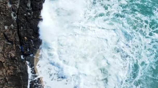Vista aérea de las olas rompen en las rocas en un océano azul, las olas del mar en la hermosa playa Aves vista de las olas del océano estrellándose contra un acantilado de roca de piedra vacía desde arriba, Chipre — Vídeos de Stock