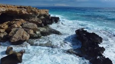 Sea washes the rocky shore, Above Aerial shot, Flying Over Coastline, Cliffside with Blue Pure Water, Ocean During Sunny weather. Bird Eye View 4K Cinematic Drone Footage. Coast From the Air, 