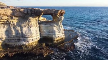 Kayalık Kıyı Hattı üzerinde Mavi Akdeniz ile birlikte Uçan Okyanus Suyu Gün Batımında Güneş 'e Doğru. Kuş Gözü Görünümü 4K Sinematik İnsansız Hava Aracı. Deniz kıyısının üzerinde Gökyüzünden, Kıbrıs.