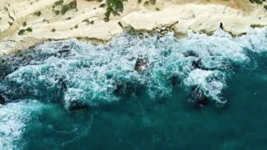 Kayalık Kıyı Hattı üzerinde Mavi Akdeniz ile birlikte Uçan Okyanus Suyu Gün Batımında Güneş 'e Doğru. Kuş Gözü Görünümü 4K Sinematik İnsansız Hava Aracı. Deniz kıyısının üzerinde Gökyüzünden, Kıbrıs.