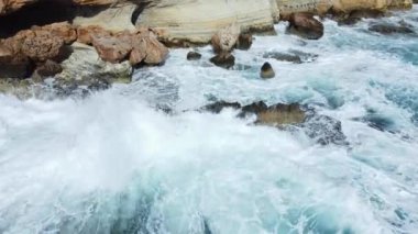 Kayalık Kıyı Hattı üzerinde Mavi Akdeniz ile birlikte Uçan Okyanus Suyu Gün Batımında Güneş 'e Doğru. Kuş Gözü Görünümü 4K Sinematik İnsansız Hava Aracı. Deniz kıyısının üzerinde Gökyüzünden, Kıbrıs.