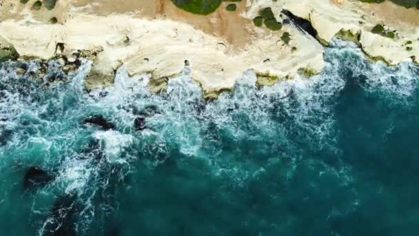 大海冲刷岩石海岸 空中射击 飞越海岸线 悬崖边与蓝色纯净的水 阳光下的海洋 鸟瞰4K电影无人机镜头 来自空中的海岸 — 图库视频影像