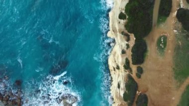 Havadan güzel bir manzara, saf mavi okyanus su dalgaları dağlara çarpıyor. Yüksek kalite 4k görüntü