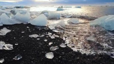 Siyah bir volkanik plajdaki buzdağları Elmas Sahili İzlanda 'daki buz parçalarını. Küresel ısınma kavramı. Aşırı yakın çekim havadan üst görüntü. Yüksek kalite 4k görüntü
