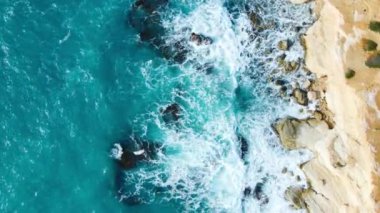 Havadan güzel bir manzara, saf mavi okyanus su dalgaları dağlara çarpıyor. Yüksek kalite 4k görüntü