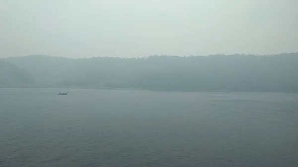 thick fog on the sea surface faintly visible fishing boats sailing