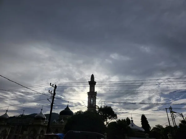 Silhouette of minarets and power lines under a cloudy sky