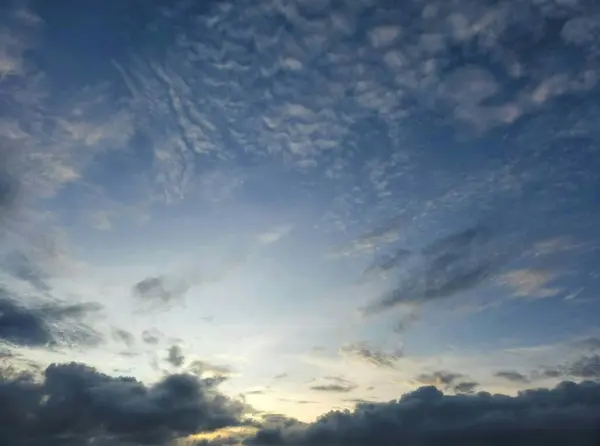 the sky at dusk with a stretch of clouds