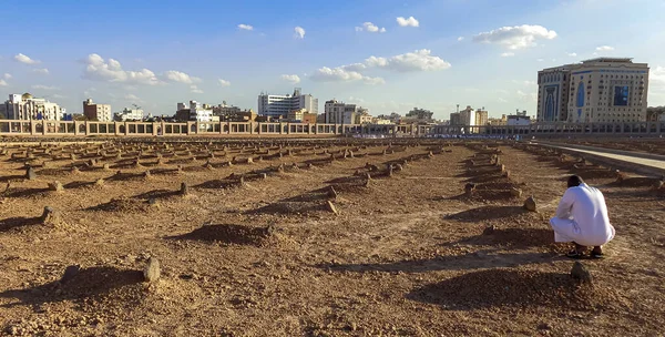 A man dressed in Arabic style sitting and crouching beside an Ancient graveyard in Medina, Saudi Arabia 
