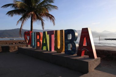 Colored Ubatuba city nameplate during sunrise at Itagua beach, Ubatuba, Brasil. High quality photo