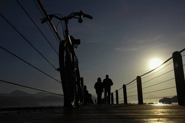Silhouette of a bicycle on a wooded bridge in the port between sunrise at Ubatuba, Brazil. High quality photo