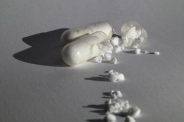 Beyaz tozlu makro kapsüllü ilaç kapsülünü aç. Beyaz kağıdın arka planına yakın çekim yap. Yüksek kalite fotoğraf