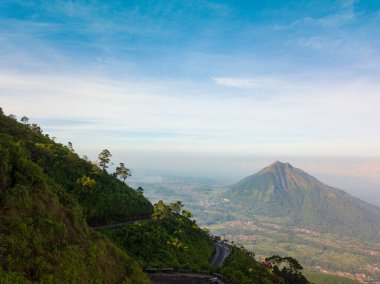 Bir dağın yamaçlarındaki yolun insansız hava aracı fotoğrafı ve arka planda Andong Dağı ile çevrili sık ormanlarla çevrili. Telomoyo Dağı 'nda açık havada, merkez java, Endonezya' da yer alır.