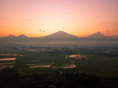 Sunrise Sky 'ın pirinç tarlasında dağlarla çekilmiş robot resmi. Endonezya 'nın kırsal arazisi