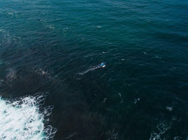 Drone photo of fishing boat in the middle of the ocean looking for fish with cloudy sky on the background