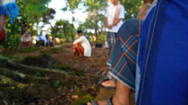 İslami cenaze töreninde beyaz başparmak taşlarıyla arka planda dua eden insanların odaksız fotoğrafı.