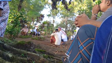 İslami cenaze töreninde beyaz başparmak taşlarıyla arka planda dua eden insanların odaksız fotoğrafı.