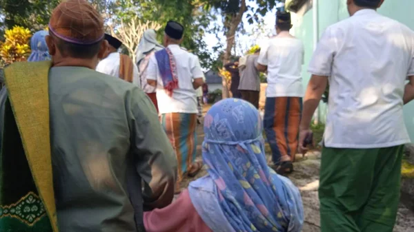 İslami cenaze töreninde beyaz başparmak taşlarıyla arka planda dua eden insanların odaksız fotoğrafı.