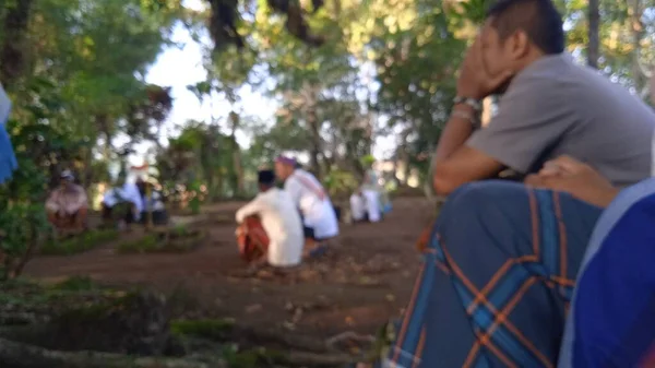 İslami cenaze töreninde beyaz başparmak taşlarıyla arka planda dua eden insanların odaksız fotoğrafı.