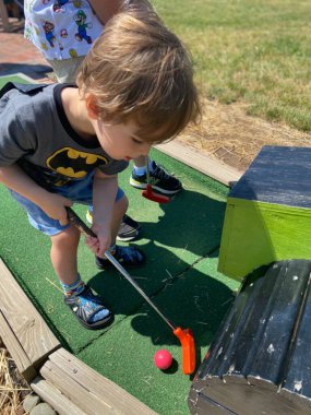 Küçük çocuk mini golf oynuyor.