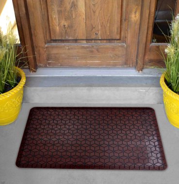 Çikolata siyah deri kaplama kapı paspası. Evin dışında sarı çiçekler ve yapraklarla.