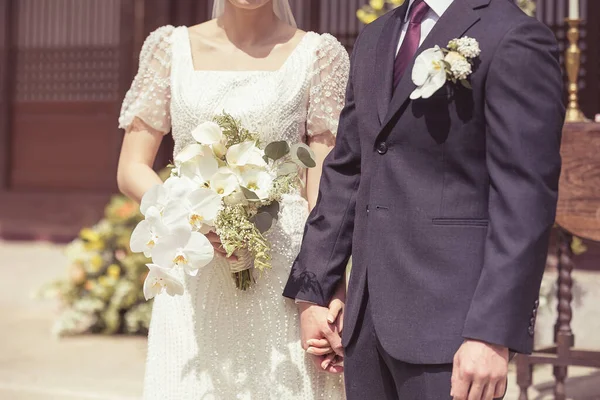 結婚式のカップルの花嫁と新郎は結婚式の日に花嫁の手で花束で手を握って — ストック写真