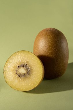 Yeşil arka planda gölgeli iki sarı kivi. Dikey fotoğraf.