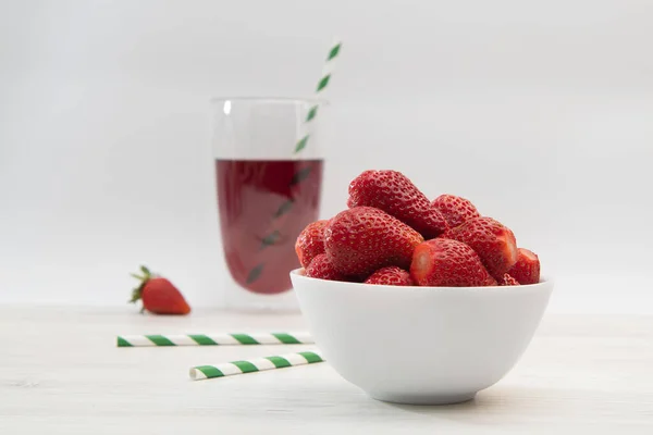 Party with strawberries and juice. Light juice background with straw. Useful breakfast.