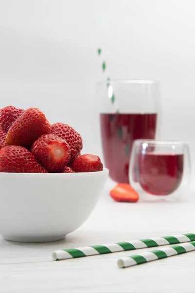 Party with strawberries and juice. Light juice background with straw. Useful breakfast.
