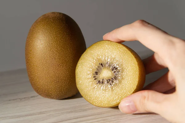 Two Cut Yellow Kiwis Gray Table Shadows Hands Close — Stock fotografie