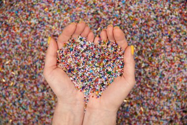 A lot of colorful beads in hands on a white background.