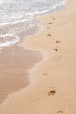 Human footprints on the beach, footprints on the yellow warm sand in summer.