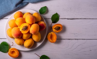 fresh apricots in a cut with a stone on a plate on a white table