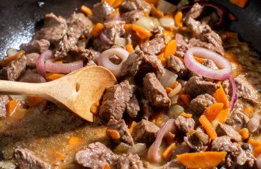 Et ve sebze, tavada pişirme sürecinde karıştırılır.