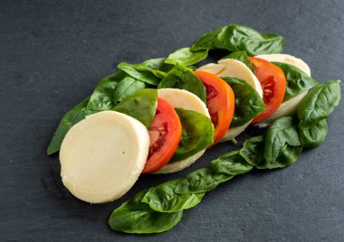 Koyu arkaplanda domates fesleğeni mozzarella sarımsağı.