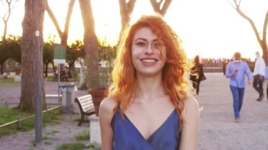Giardino degli aranci 'de yürüyen güzel kızıl saçlı kadını yavaş çekimde kameraya gülümsüyor.