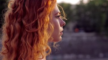 Şehirde yalnız başına üzgün genç bir kadın düşünceli bir bakışla aşağıya bakıyor.