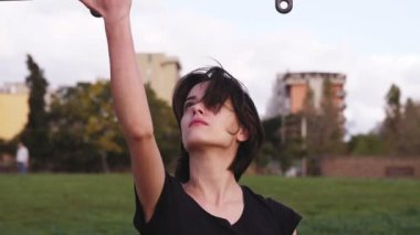 Ağır çekimde genç bir kadın büyük bir çabayla ayağa kalkmaya çalışıyor ve gülümsüyor.