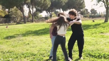 Üç genci ağır çekimde desteklemek ve parkta birbirlerine sarılmaktan mutlu olurlar.