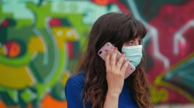 Maske takan genç ve güzel bir kadın erkek arkadaşıyla telefonda konuşuyor.