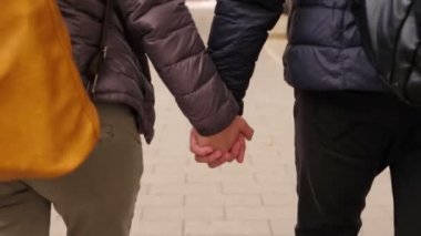 Sırt çantalı genç ve romantik bir çiftin el ele tutuşması.