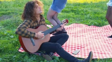 Park 'ta dans eden, gitar çalan üç arkadaşa ağır çekim.